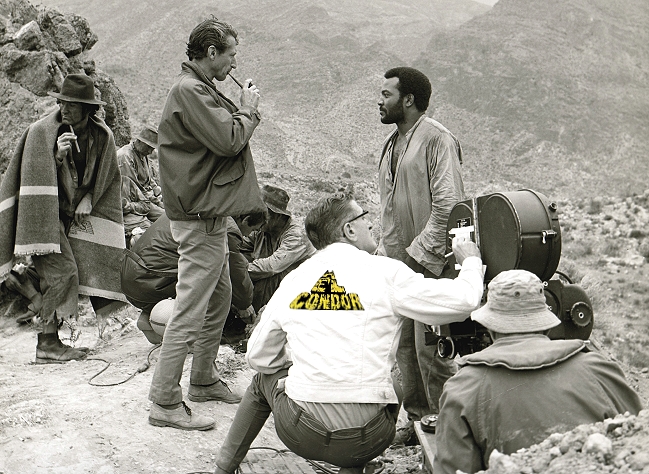 John Guillerman (L, smoking pipe) talks with actor Jim Brown (R), on the set of "El Condor" (1970).