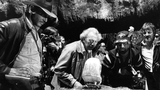 Harrison Ford (L), Douglas Slocombe (C), and Steven Spielberg (CR) and Lawrence Kasdan (R) on the set of Raiders of the Lost Ark (1981). 